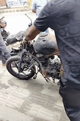Man moves fire-damaged motorcycle in Dhaka
