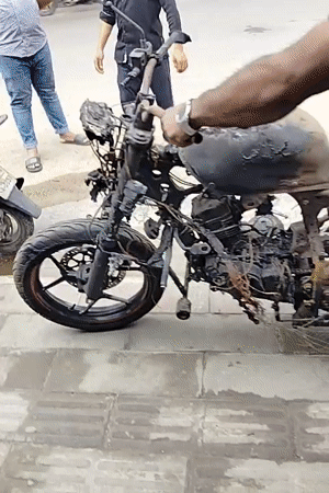 Man moves fire-damaged motorcycle in Dhaka
