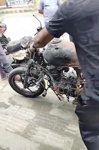 Man moves fire-damaged motorcycle in Dhaka