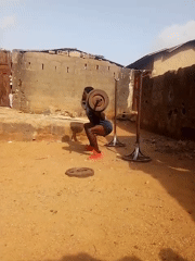 Man performs outdoor barbell squats on unpaved ground