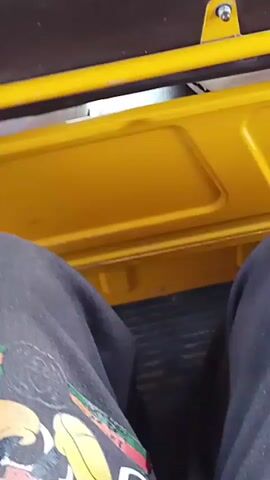 The video shows the interior of a vehicle, possibly a bus or van, with two passengers in the foreground. The camera is looking forward through a window, providing a view of the road ahead. Several tuk-tuks and what appear to be police officers are visible on the road, suggesting a public street in a busy area. The overall lighting and color palette suggest it is daytime. The camera appears to be mounted inside the vehicle and is panning slightly.