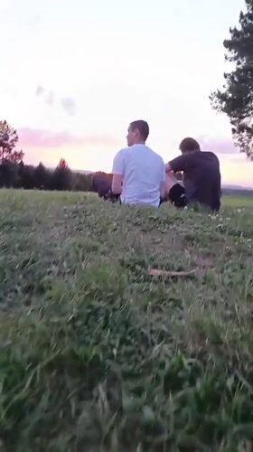 Two men watch sunset on hilltop near Chuma, Russia