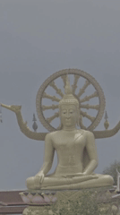 Golden Buddha statue overlooks Thai waterfront village scene