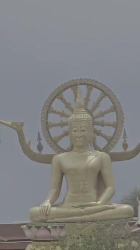 Golden Buddha statue overlooks Thai waterfront village scene