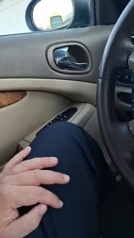 The video shows a person sitting in the driver's seat of a Jaguar. The focus is on the car's interior, particularly the steering wheel and dashboard. The steering wheel is brown leather with a Jaguar logo in the center. The dashboard features wood trim and a radio console. The person's hand is seen tapping on the steering wheel. The car's interior is a combination of beige and brown colors.