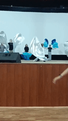 Children perform with flowing fabric on indoor stage