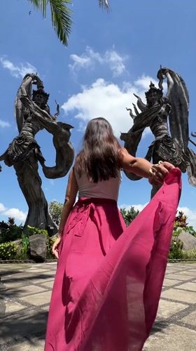 Tourist documents traditional Balinese sculptures in Kedewatan garden setting