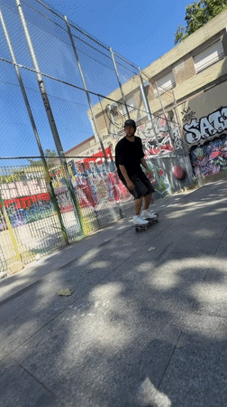 Skateboarder practices tricks at Barcelona park on sunny afternoon
