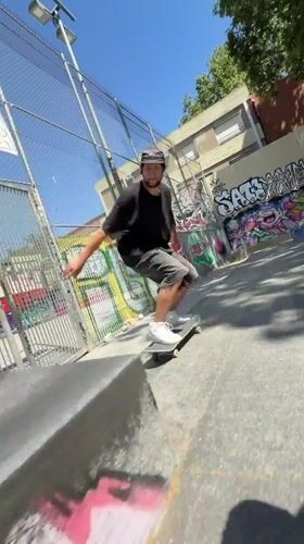 Skateboarder practices tricks at Barcelona park on sunny afternoon