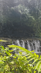 Man in traditional Balinese dress walks near waterfall in Susut
