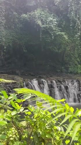 Man in traditional Balinese dress walks near waterfall in Susut