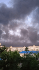 Heavy smoke plume rises over residential area at dusk