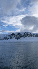 Vessel documents calm Antarctic waters amid snow-covered peaks