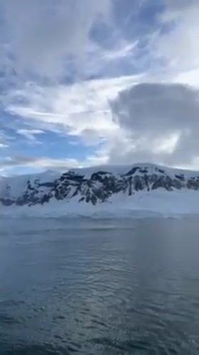 Vessel documents calm Antarctic waters amid snow-covered peaks