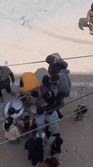 Children and adults gather around metal bowls in urban space