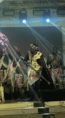Traditional performer sings on illuminated stage in Jos, Nigeria