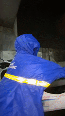 Child in blue rain poncho seeks shelter during rainfall