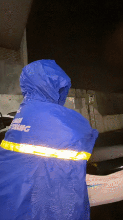 Child in blue rain poncho seeks shelter during rainfall
