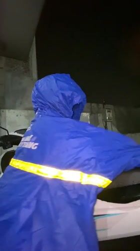Child in blue rain poncho seeks shelter during rainfall