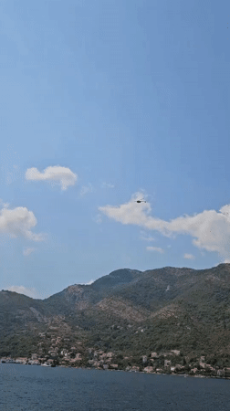 Helicopter cuts across the mountains above Boka Bay