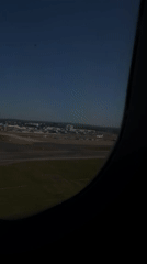 Passenger films airport view from airplane window over Crawley