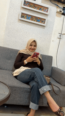 Woman uses phone on couch in decorated Lhokseumawe home