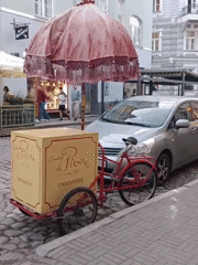 Ornate pink-umbrella tricycle cart parked on Tallinn's cobblestone streets