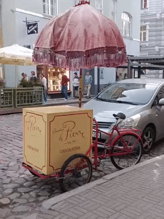 Ornate pink-umbrella tricycle cart parked on Tallinn's cobblestone streets