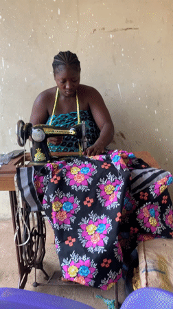 Woman sews floral fabric at vintage machine in Akwanga