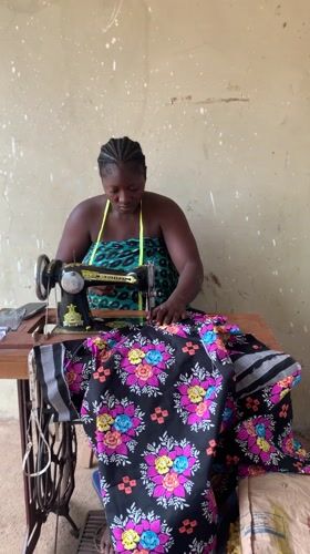 Woman sews floral fabric at vintage machine in Akwanga