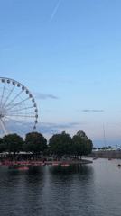 Ferris wheel and red pedal boats at a busy waterfront