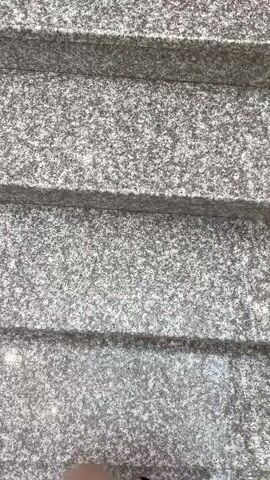 A first-person perspective video shows a person descending a flight of stairs. The stairs appear to be made of granite with a speckled gray pattern. The person is wearing a black dress with a white floral pattern and black open-toed heels. The camera angle focuses on the steps and the person's feet as they move down.