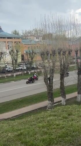 Flag-bearing motorcyclists parade through Russian town amid street life