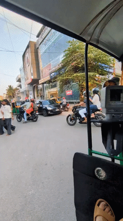 Auto-rickshaw passenger documents busy Bengaluru street scene