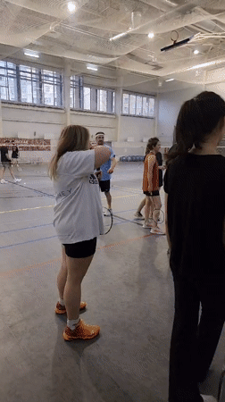 Recreational badminton session in an indoor gymnasium.