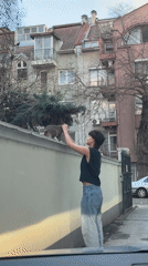 Woman pets tabby cat on wall in Plovdiv
