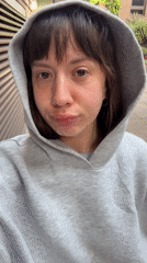 Person in gray hoodie films outdoor statement in London