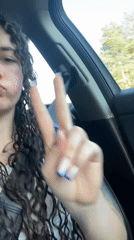 Woman makes playful gestures in car along Greek roadway