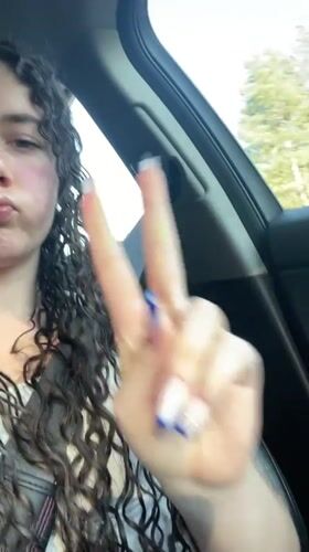 Woman makes playful gestures in car along Greek roadway