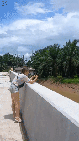 Woman photographs rural waterway scenery in Na Nuea, Thailand