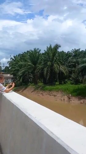 Woman photographs rural waterway scenery in Na Nuea, Thailand