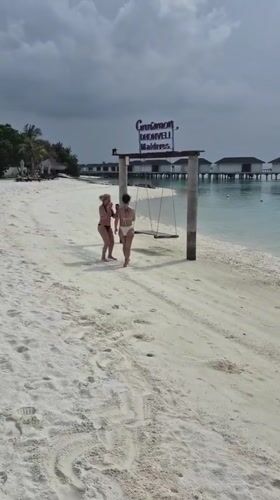 Two women visit Maldives resort beach at dawn