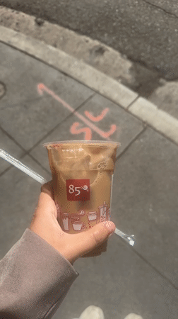 Person enjoys 85°C iced coffee on Hope Street sidewalk