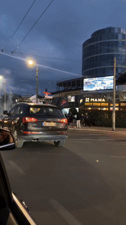 People gather with banners on Belgrade street at dusk