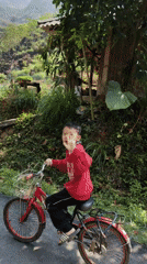 Boy cycles through Vietnam's green mountains, waves at observers