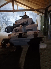 Historical tank display observed in wooden building with visitors