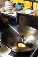 Street cook prepares fried eggs at Lhokseumawe food station