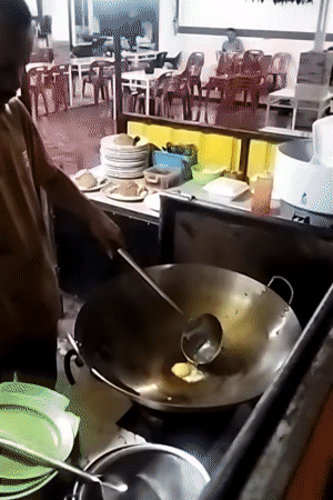 Street cook prepares fried eggs at Lhokseumawe food station