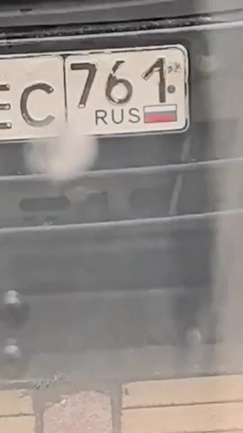 The video shows a close-up of the rear of a vehicle, focusing on its license plates. The first license plate visible is from Russia and displays "EC 761" with the Russian flag and "RUS" below the numbers. The second license plate partially visible shows "68EC 76" and the Russian flag. The third license plate reads "H568". The vehicle appears to be dirty, with a hazy or dusty appearance. The background is dark and out of focus, suggesting it is nighttime or the image is taken in low light conditions.