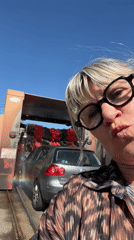 Woman takes selfie at active car wash in Chambœuf